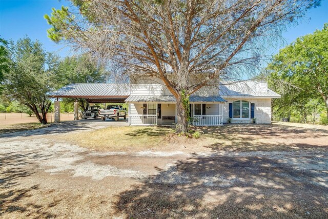 ranch-style house featuring covered porch and a carport