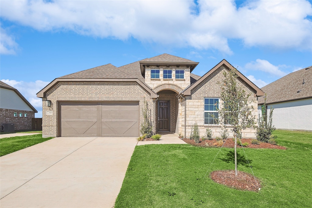 view of front of home featuring cooling unit, a front lawn, and a garage