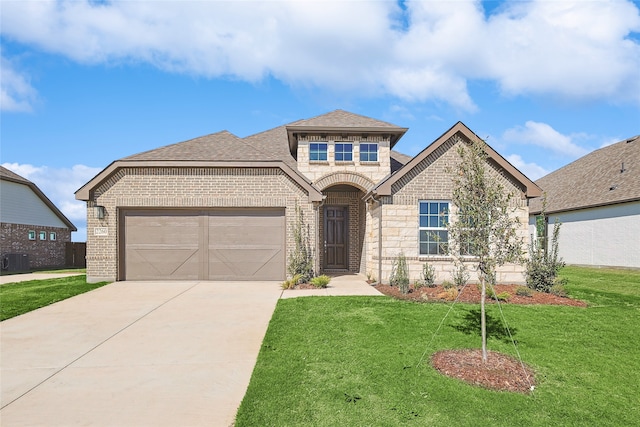 view of front of home featuring cooling unit, a front lawn, and a garage