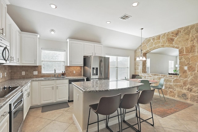 kitchen featuring a healthy amount of sunlight, appliances with stainless steel finishes, light stone counters, and sink