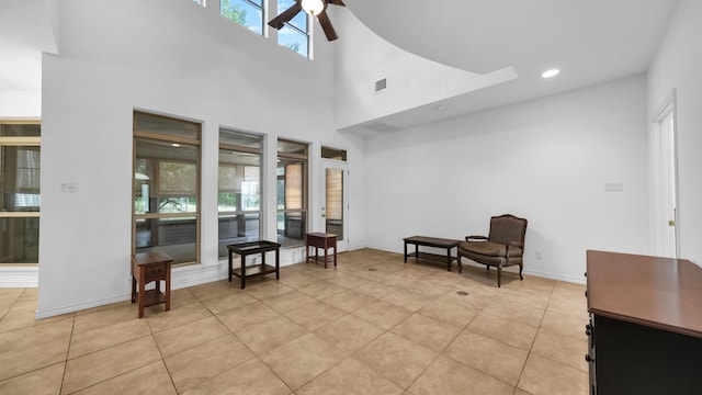 sitting room with light tile patterned floors, a towering ceiling, and ceiling fan