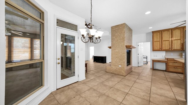 kitchen with light tile patterned floors, ceiling fan with notable chandelier, decorative light fixtures, and a large fireplace