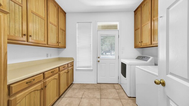 washroom with cabinets, washing machine and dryer, and light tile patterned floors