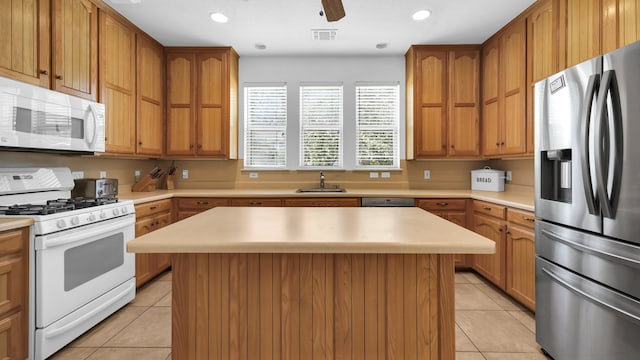 kitchen featuring a center island, white appliances, sink, and light tile patterned floors