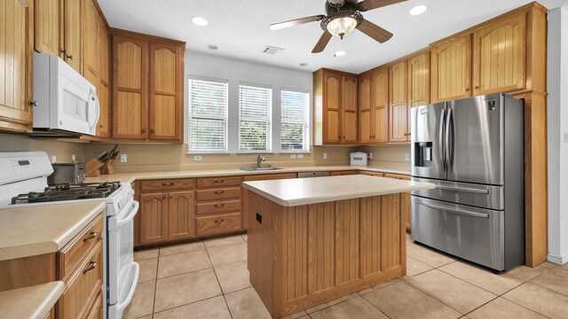 kitchen with ceiling fan, a center island, sink, white appliances, and light tile patterned flooring