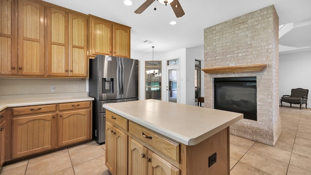 kitchen featuring a fireplace, ceiling fan with notable chandelier, stainless steel refrigerator with ice dispenser, and light tile patterned floors