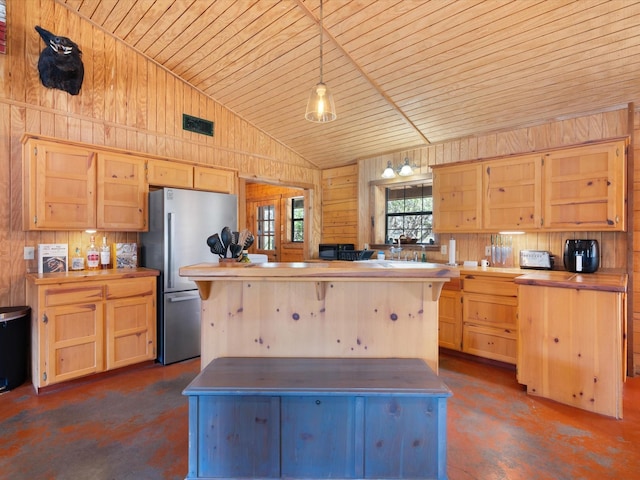 kitchen with stainless steel fridge, wooden walls, pendant lighting, and light brown cabinets