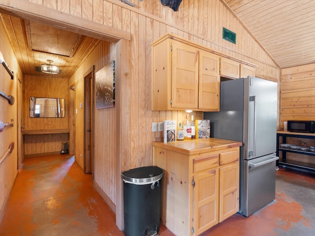 kitchen with light brown cabinetry, concrete floors, wooden walls, and wood ceiling