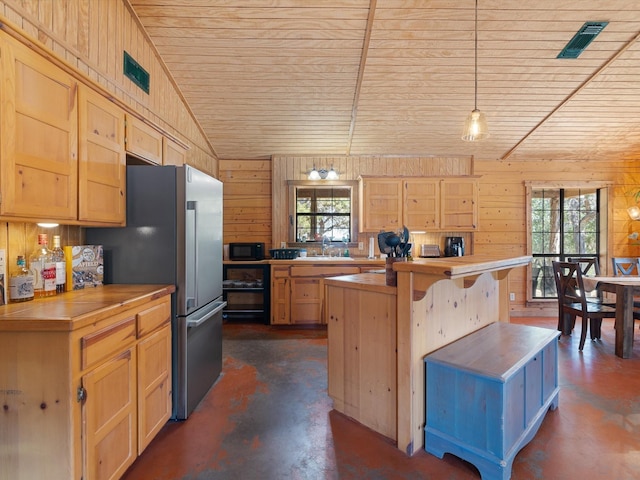 kitchen with butcher block counters, wood walls, plenty of natural light, and pendant lighting