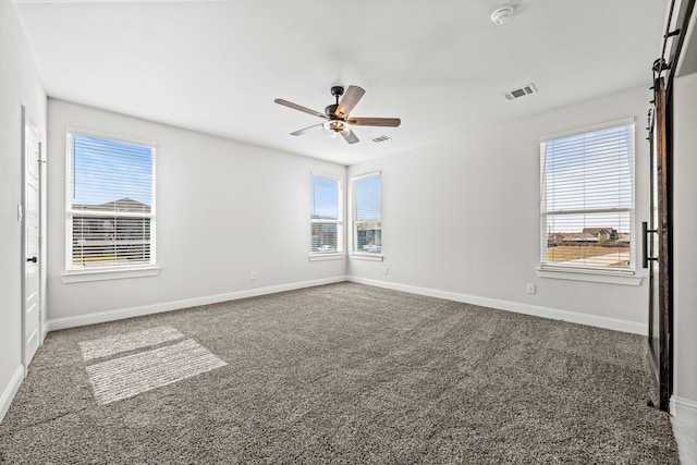 carpeted bedroom featuring a barn door, ensuite bathroom, ceiling fan, a closet, and a walk in closet