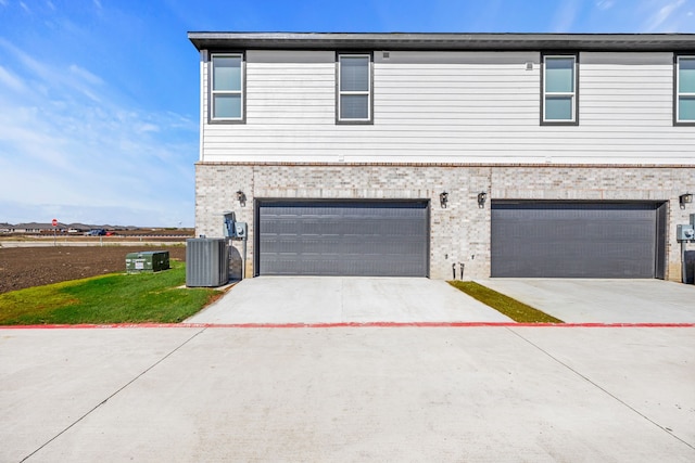 view of front of home featuring central air condition unit and a garage