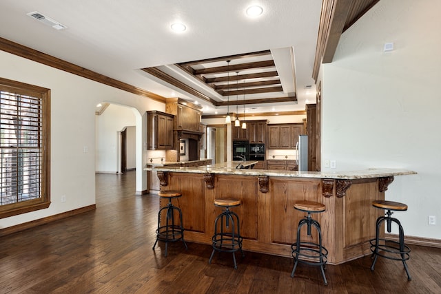 kitchen with kitchen peninsula, a kitchen bar, a raised ceiling, dark wood-type flooring, and crown molding