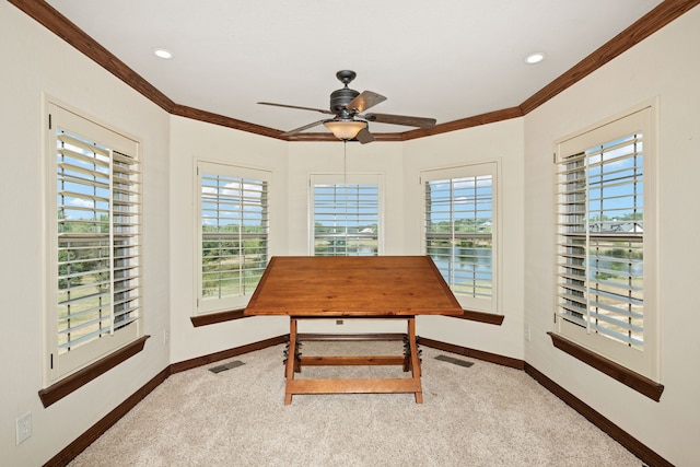 carpeted dining space with crown molding and ceiling fan