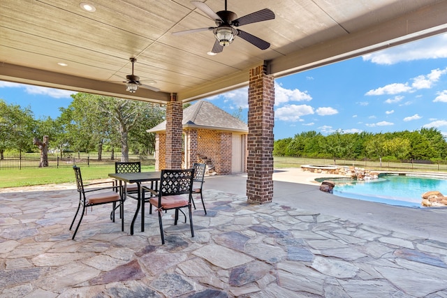 view of patio with ceiling fan and a pool with hot tub