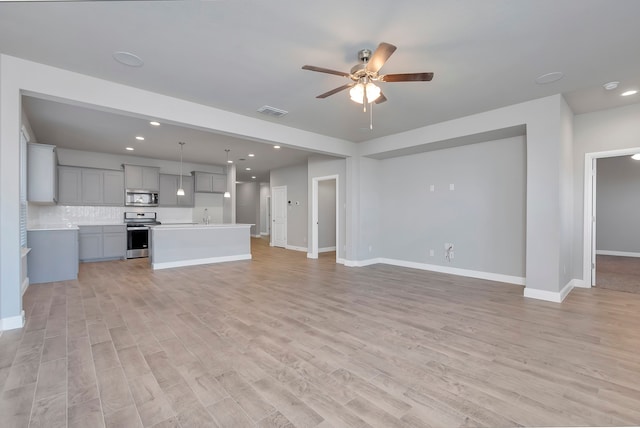 unfurnished living room with sink, light hardwood / wood-style flooring, and ceiling fan