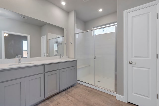 bathroom with plenty of natural light, wood-type flooring, a shower with door, and dual bowl vanity