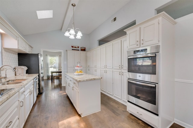 kitchen featuring light stone counters, sink, appliances with stainless steel finishes, and a kitchen island