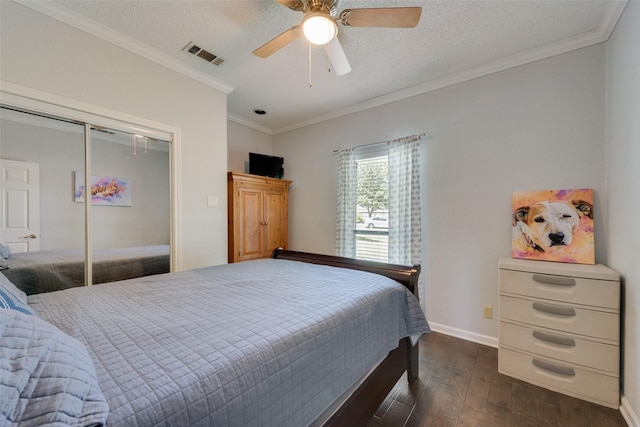 bedroom featuring a textured ceiling, ornamental molding, dark hardwood / wood-style flooring, a closet, and ceiling fan