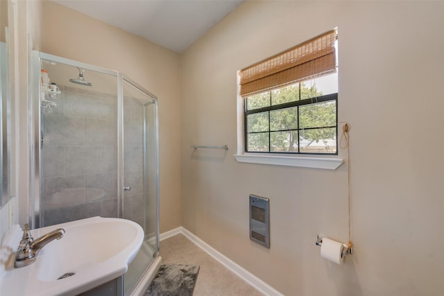 bathroom with heating unit, sink, a shower with door, and tile patterned floors