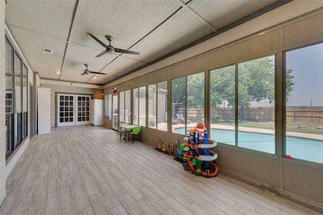 unfurnished sunroom featuring ceiling fan and french doors