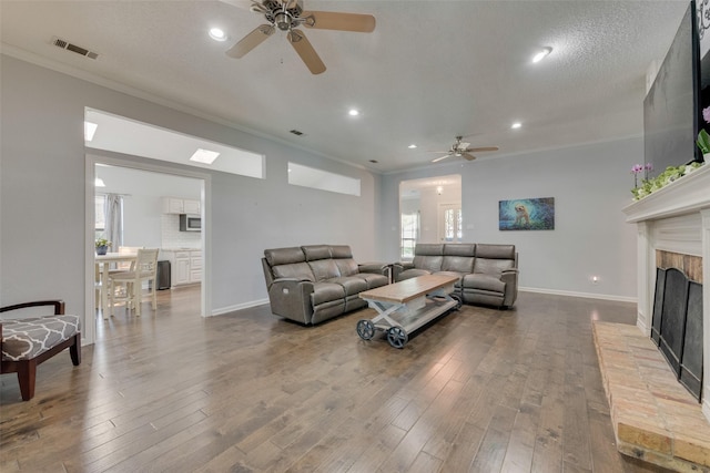 living room with crown molding, wood-type flooring, a textured ceiling, and ceiling fan