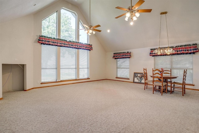 carpeted dining area with ceiling fan, plenty of natural light, and high vaulted ceiling