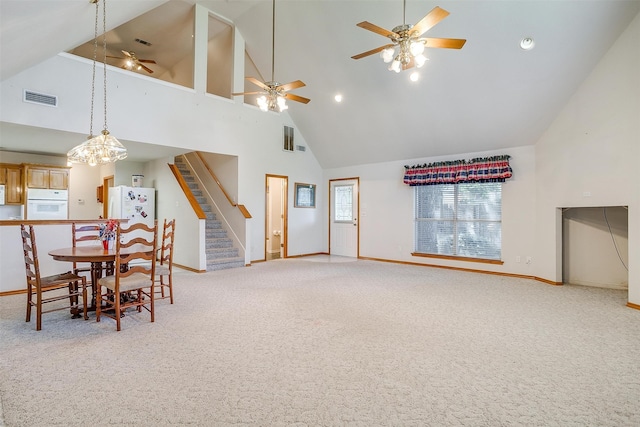 carpeted dining room with ceiling fan and high vaulted ceiling