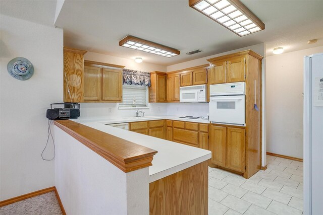 kitchen featuring white appliances, kitchen peninsula, and sink