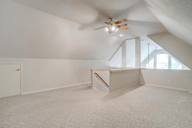 additional living space with light colored carpet, vaulted ceiling, and a textured ceiling