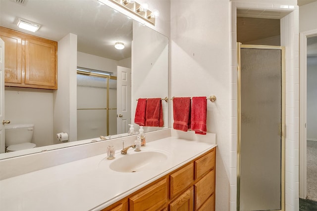 bathroom featuring a shower with door, vanity, and toilet