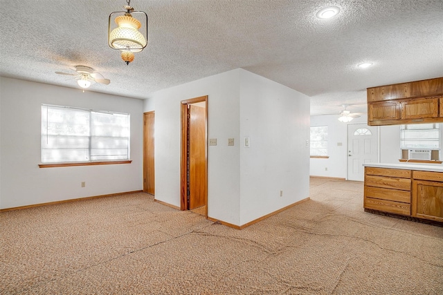 interior space with hanging light fixtures, light colored carpet, a textured ceiling, and ceiling fan