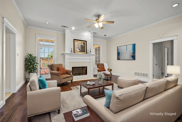 living room featuring a tile fireplace, crown molding, dark wood-type flooring, and ceiling fan