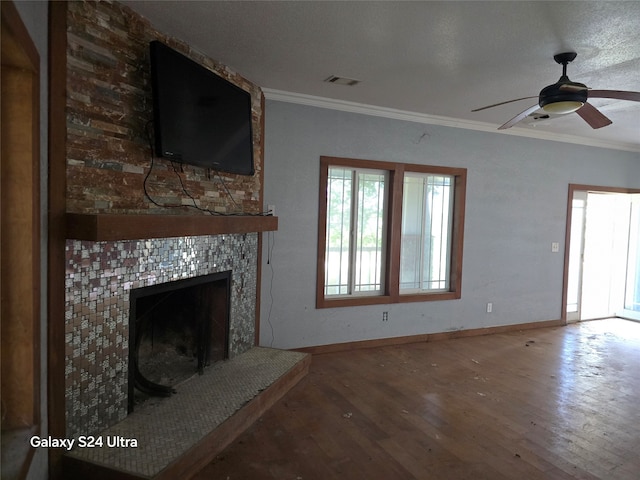 unfurnished living room featuring a fireplace, a textured ceiling, ceiling fan, wood-type flooring, and ornamental molding