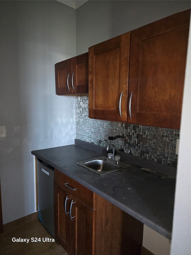 kitchen with hardwood / wood-style floors, stainless steel dishwasher, sink, and backsplash