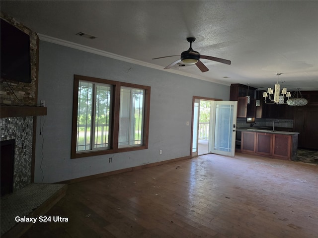 unfurnished living room featuring a stone fireplace, ceiling fan with notable chandelier, hardwood / wood-style flooring, and ornamental molding