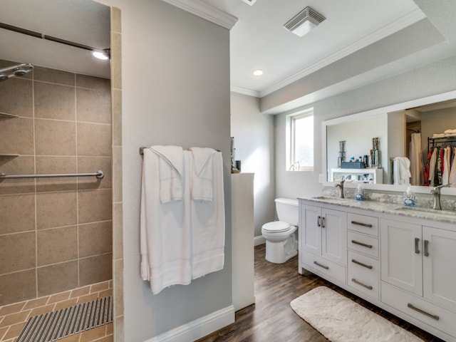 bathroom featuring tiled shower, crown molding, toilet, vanity, and wood-type flooring