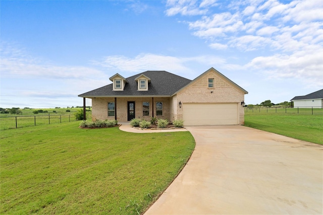 view of front of home with a front lawn, a rural view, a porch, and a garage