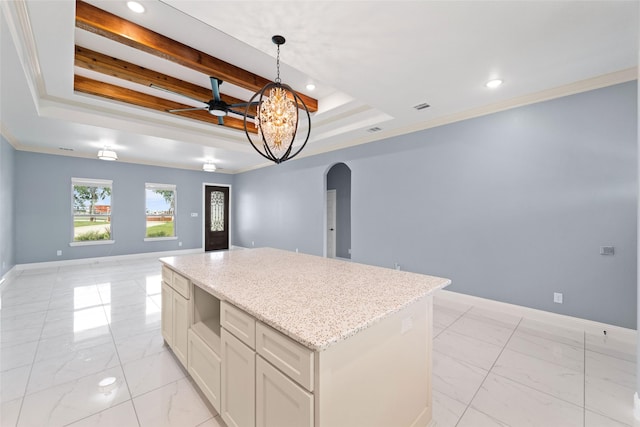 kitchen with a center island, a raised ceiling, crown molding, and hanging light fixtures