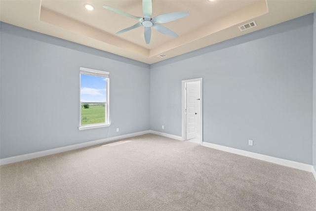 carpeted spare room featuring a raised ceiling and ceiling fan