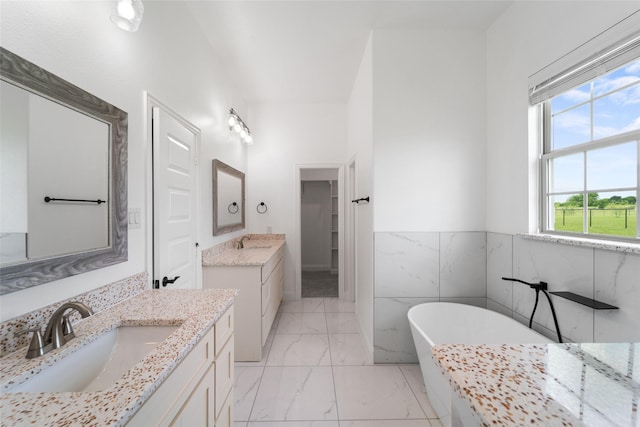 bathroom featuring a washtub, vanity, and tile walls