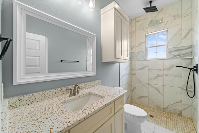 bathroom featuring a tile shower, vanity, and toilet