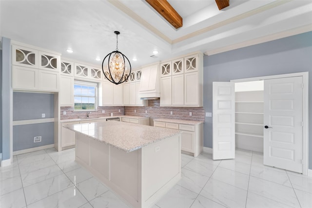 kitchen featuring custom exhaust hood, a center island, light stone countertops, decorative light fixtures, and white cabinetry