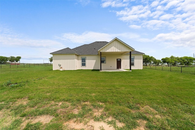 rear view of house featuring a lawn, a patio area, and a rural view