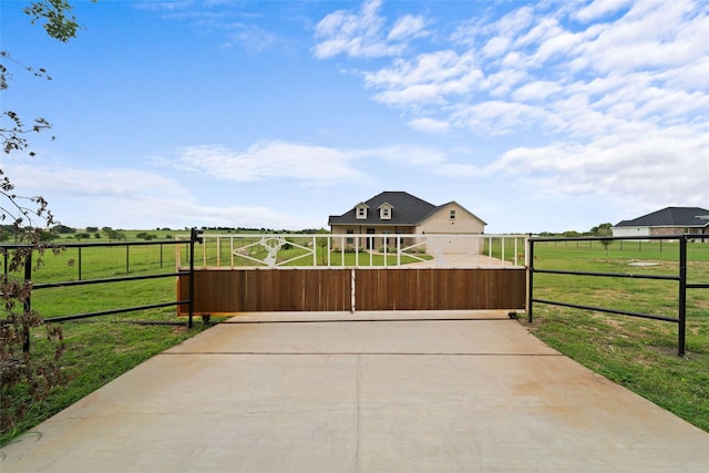 view of gate featuring a lawn and a rural view