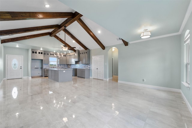 kitchen featuring decorative backsplash, wall chimney range hood, pendant lighting, beam ceiling, and a kitchen island