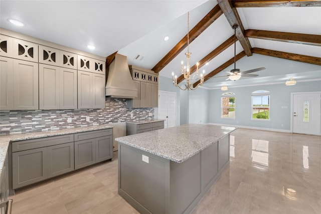 kitchen with custom range hood, ceiling fan with notable chandelier, beam ceiling, a center island, and gray cabinets