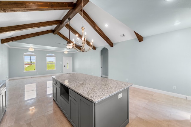 kitchen with lofted ceiling with beams, ceiling fan with notable chandelier, gray cabinets, a kitchen island, and light stone counters