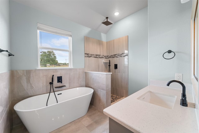 bathroom featuring vanity, separate shower and tub, tile walls, and vaulted ceiling