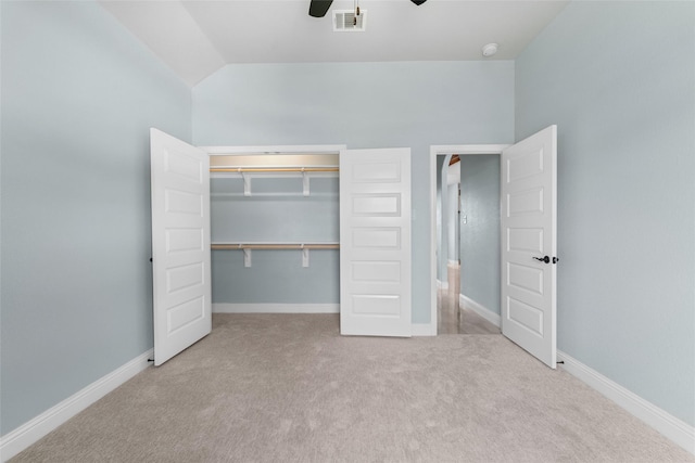 unfurnished bedroom featuring ceiling fan, vaulted ceiling, light carpet, and a closet