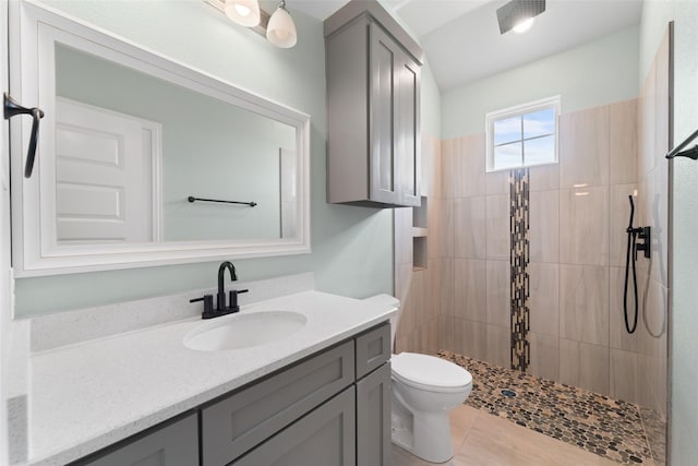 bathroom featuring tile patterned floors, toilet, vanity, and tiled shower